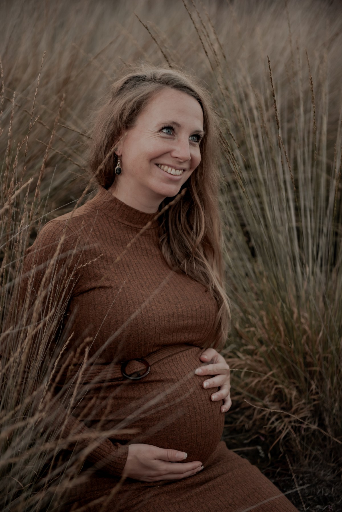 Lachende zwangere vrouw in het hoge gras