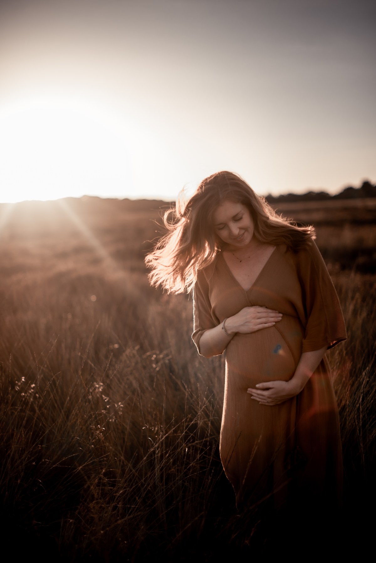 Zwangere vrouw in tegenlicht in een veld